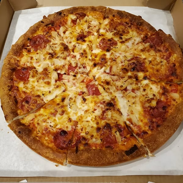 Nicolini House of Pizza pepperoni and pineapple pizza, sliced and ready to eat in a delivery box.