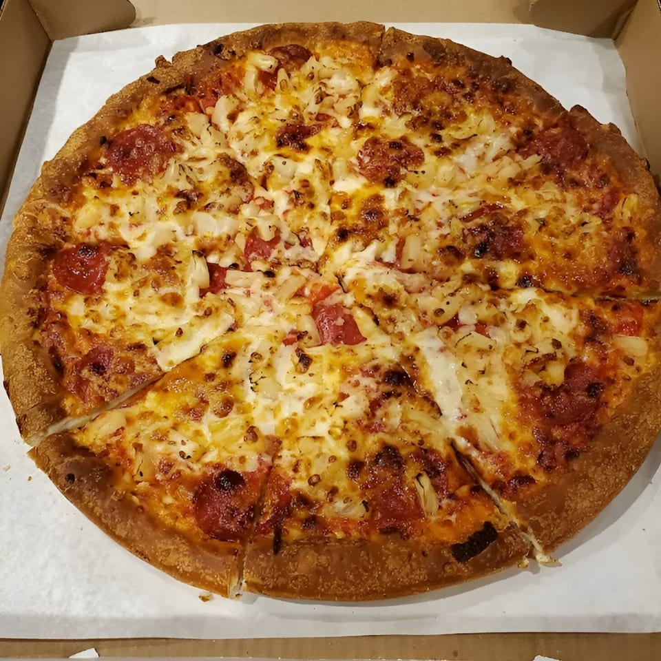 Nicolini House of Pizza pepperoni and pineapple pizza, sliced and ready to eat in a delivery box.